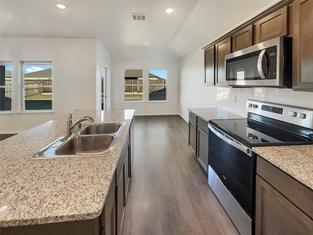 kitchen featuring sink, tasteful backsplash, dark hardwood / wood-style floors, an island with sink, and stainless steel appliances