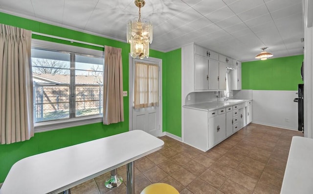 kitchen featuring white cabinetry, sink, hanging light fixtures, crown molding, and oven