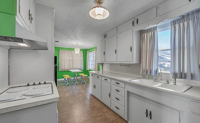 kitchen featuring white stovetop, decorative light fixtures, white cabinetry, and sink