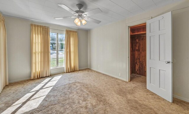 carpeted empty room featuring ceiling fan and wooden walls