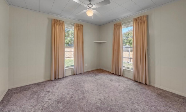 carpeted empty room with a wealth of natural light, crown molding, and ceiling fan