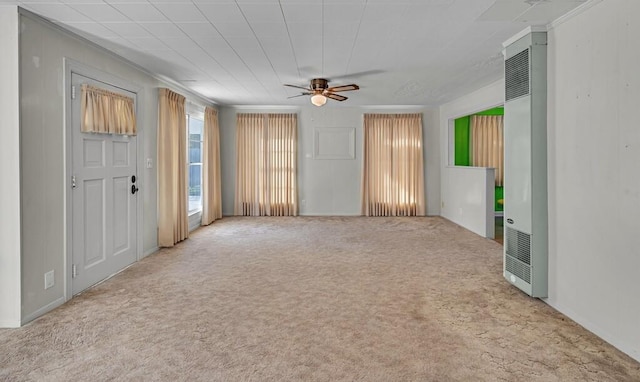 unfurnished living room featuring ceiling fan, ornamental molding, and light carpet