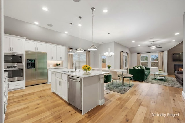 kitchen with white cabinetry, sink, a kitchen island with sink, appliances with stainless steel finishes, and light wood-type flooring