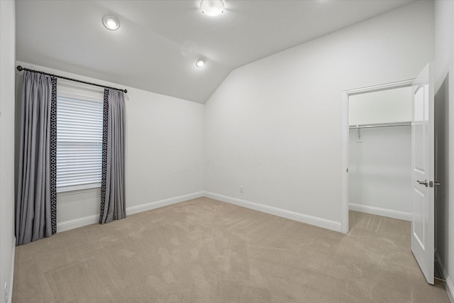 spare room featuring light carpet and vaulted ceiling