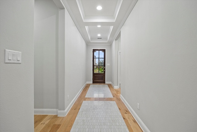 doorway to outside featuring a raised ceiling, ornamental molding, and light wood-type flooring