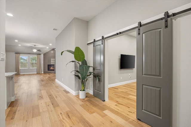 hallway featuring a barn door and light hardwood / wood-style flooring