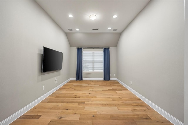 unfurnished room with light wood-type flooring and lofted ceiling