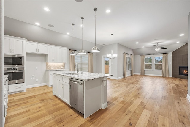 kitchen featuring stainless steel appliances, sink, a center island with sink, white cabinetry, and hanging light fixtures