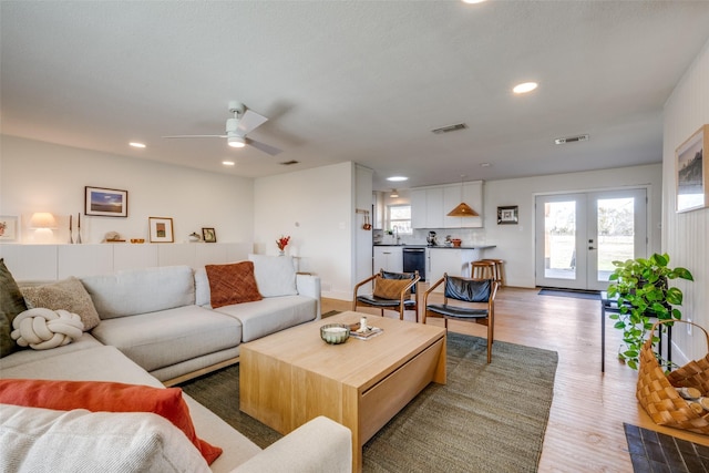 living room with ceiling fan, light hardwood / wood-style flooring, and french doors