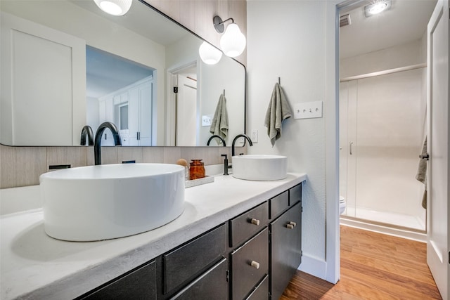 bathroom with hardwood / wood-style floors, vanity, a shower with shower door, and toilet