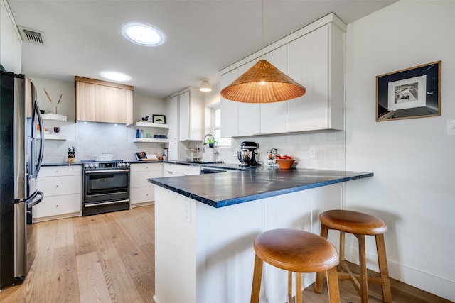 kitchen featuring a peninsula, visible vents, range with gas stovetop, stainless steel refrigerator with ice dispenser, and open shelves