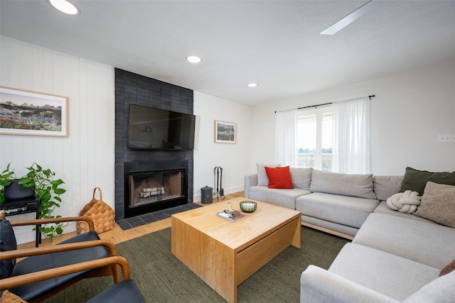 living room featuring dark hardwood / wood-style flooring, wood walls, and a large fireplace