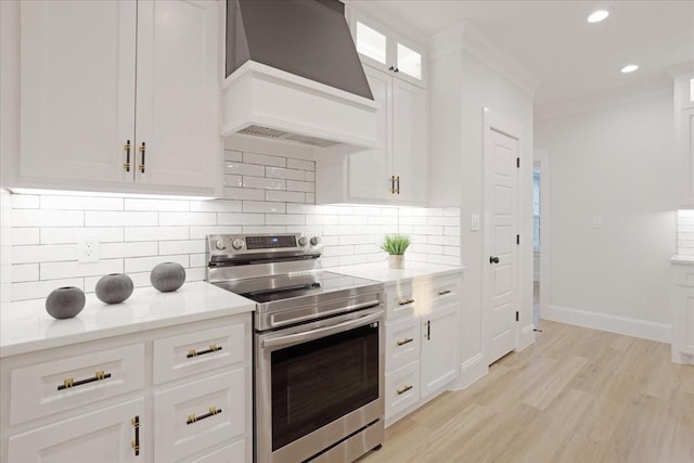 kitchen featuring light stone countertops, stainless steel range with electric cooktop, light hardwood / wood-style floors, white cabinets, and custom exhaust hood