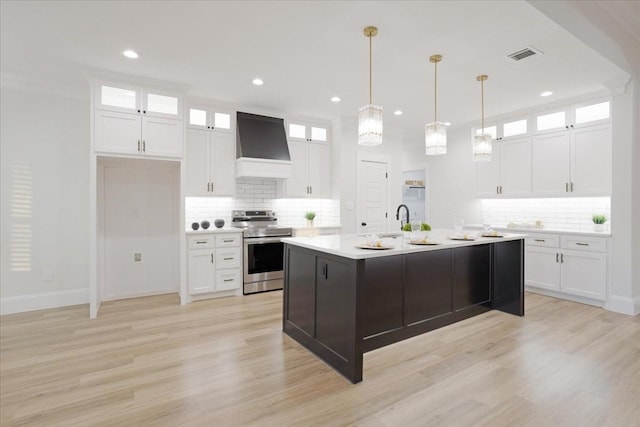 kitchen with white cabinetry, an island with sink, stainless steel electric range, custom range hood, and light wood-type flooring