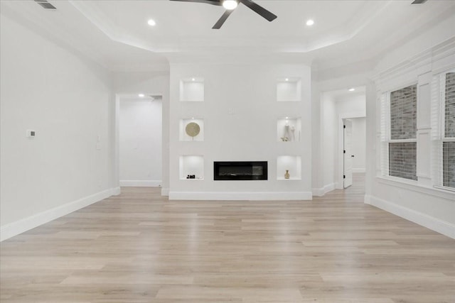 unfurnished living room featuring ceiling fan, crown molding, a tray ceiling, and light hardwood / wood-style flooring