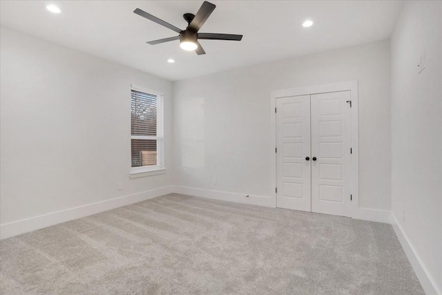 unfurnished bedroom featuring a closet, light colored carpet, and ceiling fan