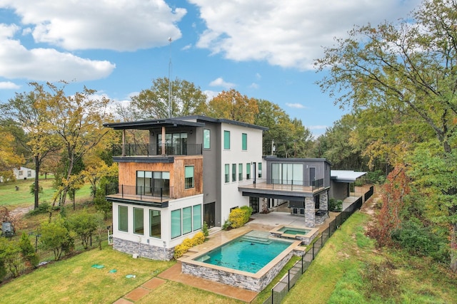 back of house featuring a swimming pool with hot tub, a yard, a balcony, and a patio