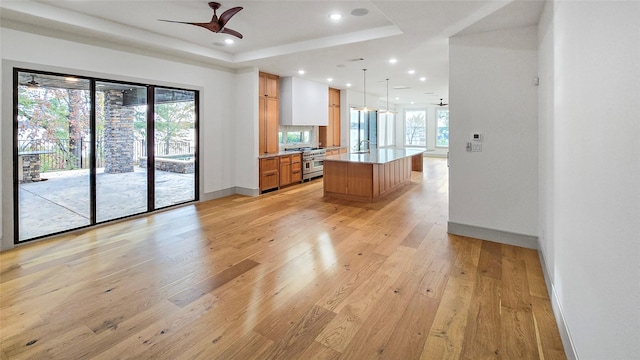 kitchen with ceiling fan, range with two ovens, decorative light fixtures, a kitchen island, and light wood-type flooring