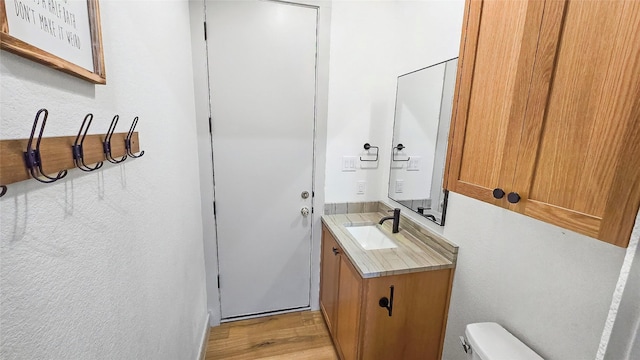 bathroom with hardwood / wood-style floors, vanity, and toilet