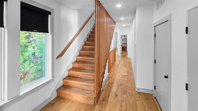 stairs with a healthy amount of sunlight and wood-type flooring