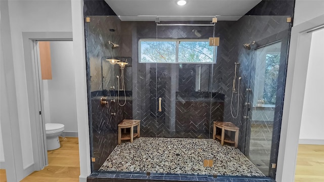 bathroom with hardwood / wood-style floors, toilet, and a shower with shower door