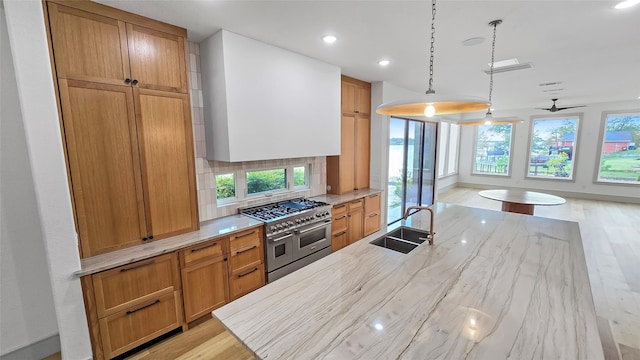 kitchen with ceiling fan, sink, light hardwood / wood-style flooring, double oven range, and decorative light fixtures