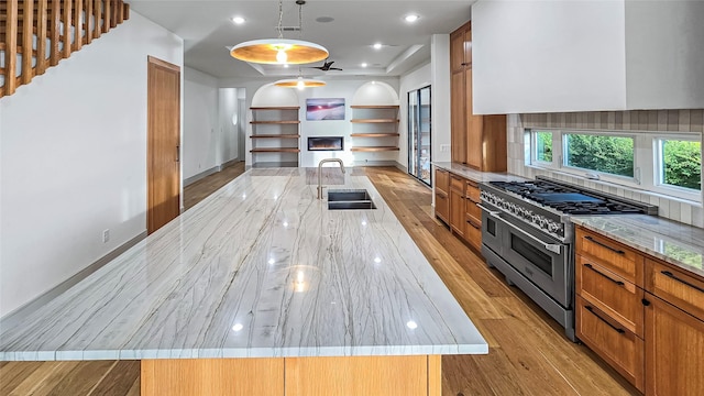 kitchen with a large island, sink, decorative light fixtures, and range with two ovens