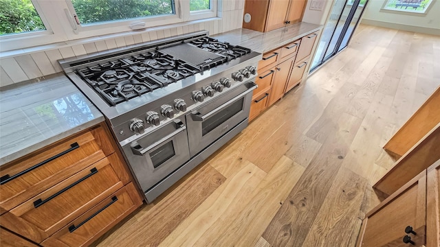 kitchen with light hardwood / wood-style flooring, refrigerator, and range with two ovens