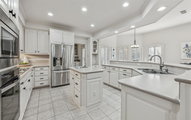 kitchen featuring appliances with stainless steel finishes, a kitchen island, sink, white cabinetry, and hanging light fixtures