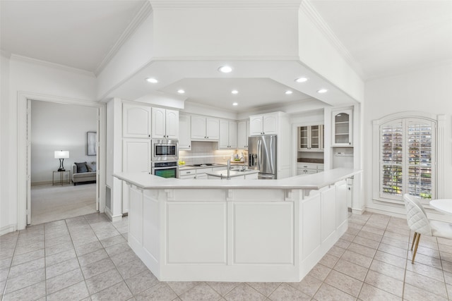 kitchen with a large island with sink, stainless steel appliances, white cabinetry, and ornamental molding