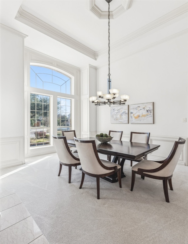 carpeted dining space with an inviting chandelier, crown molding, a raised ceiling, and a towering ceiling