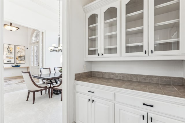 bar with white cabinetry, crown molding, and tile countertops