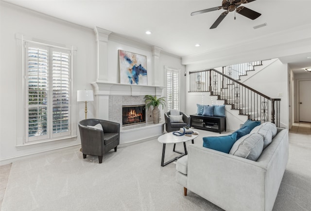 living room with a tile fireplace, ceiling fan, light carpet, and ornamental molding