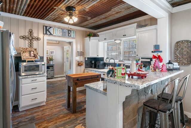 kitchen featuring kitchen peninsula, white cabinetry, dark hardwood / wood-style flooring, and appliances with stainless steel finishes