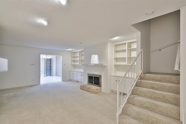 unfurnished living room featuring a chandelier, light colored carpet, a textured ceiling, and a fireplace