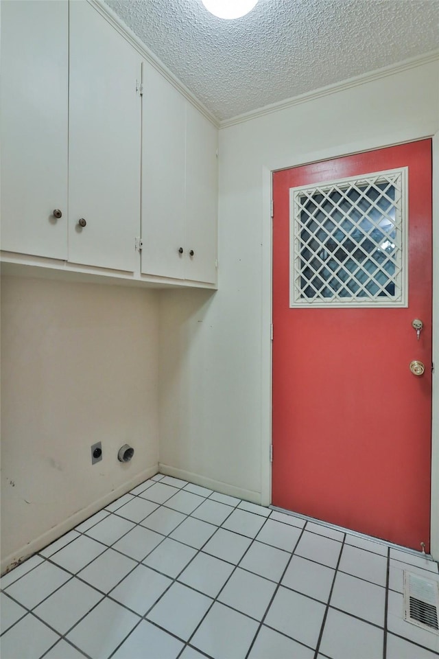 washroom featuring electric dryer hookup, cabinets, a textured ceiling, and light tile patterned flooring