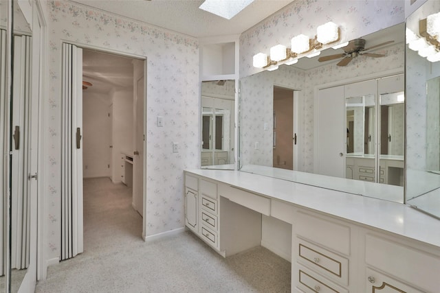 bathroom featuring vanity, ceiling fan, a skylight, and a textured ceiling