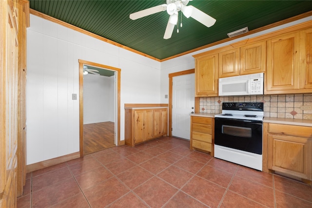 kitchen featuring white appliances, dark tile patterned flooring, wood walls, and backsplash