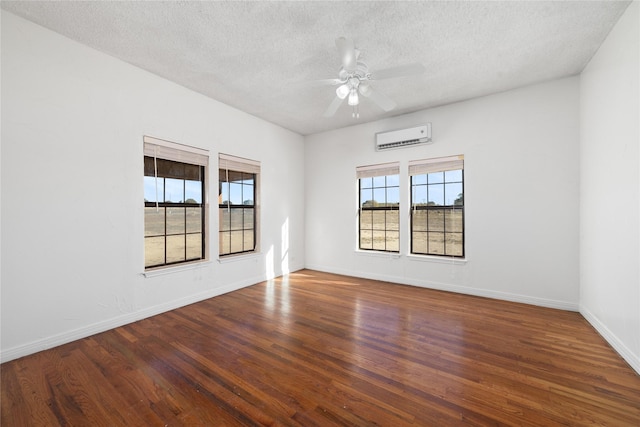 spare room with a wall mounted air conditioner, a textured ceiling, and dark hardwood / wood-style flooring