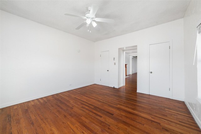 unfurnished bedroom with ceiling fan, dark hardwood / wood-style flooring, and a textured ceiling