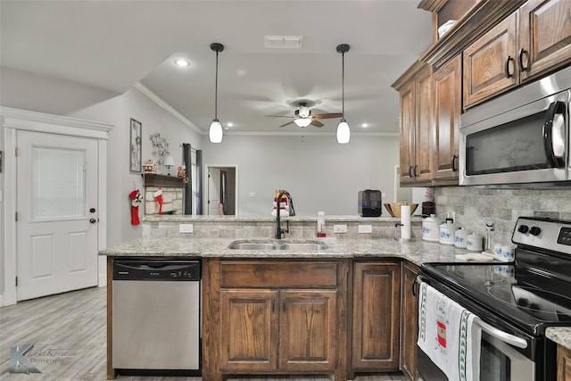 kitchen with kitchen peninsula, stainless steel appliances, ceiling fan, crown molding, and sink