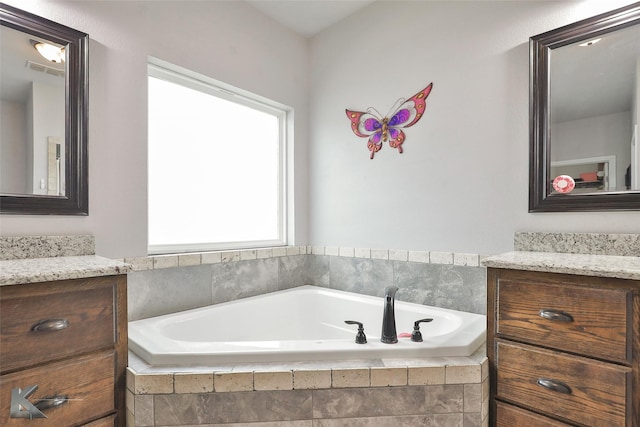 bathroom with vanity and tiled tub