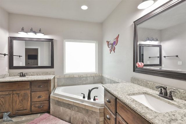 bathroom with tiled tub and vanity