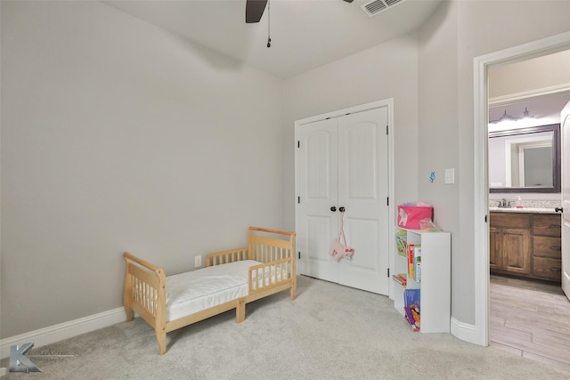 carpeted bedroom with ceiling fan, ensuite bathroom, sink, and a closet