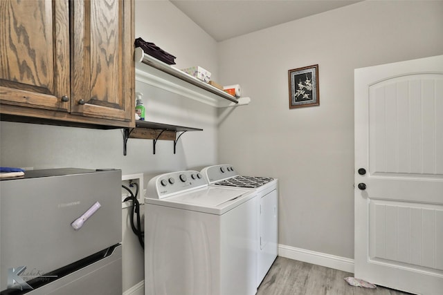 clothes washing area featuring cabinets, light hardwood / wood-style floors, and washing machine and clothes dryer