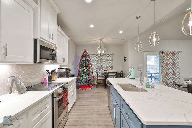 kitchen with sink, stainless steel appliances, white cabinets, blue cabinets, and decorative light fixtures