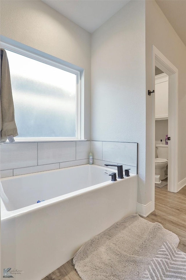 bathroom with a bath, wood-type flooring, and toilet