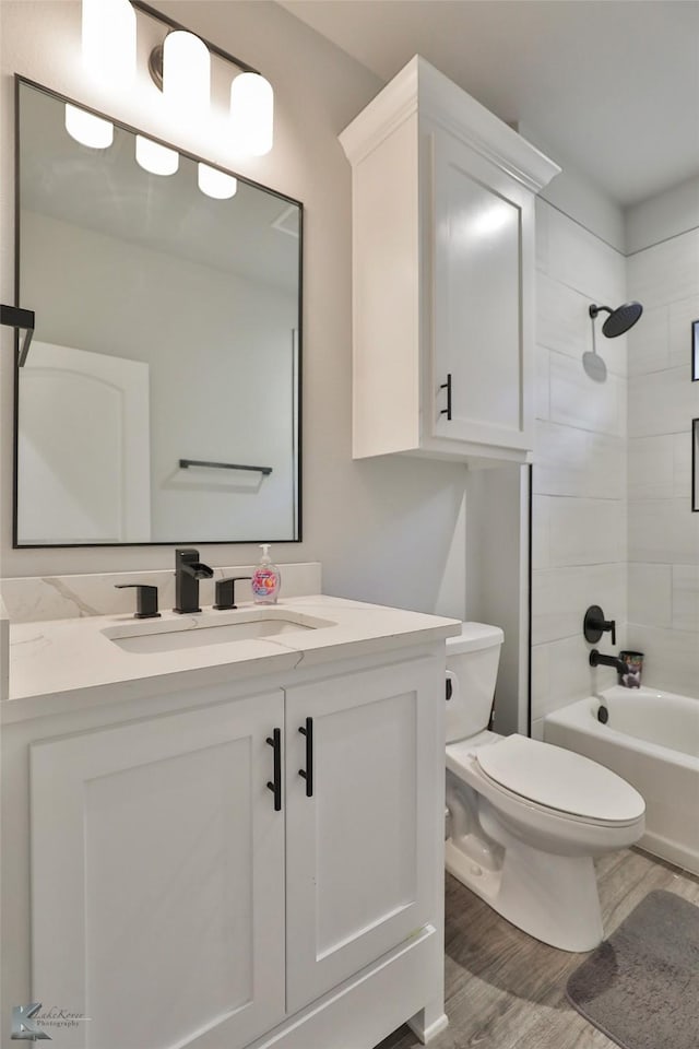 full bathroom featuring vanity, hardwood / wood-style flooring, toilet, and tiled shower / bath