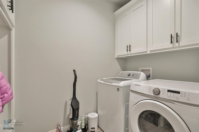 clothes washing area with cabinets and washing machine and clothes dryer