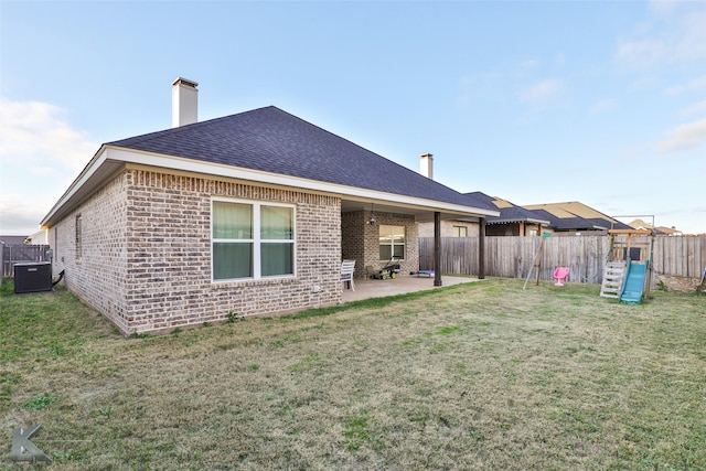 rear view of house featuring central AC unit, a yard, a patio, and a playground